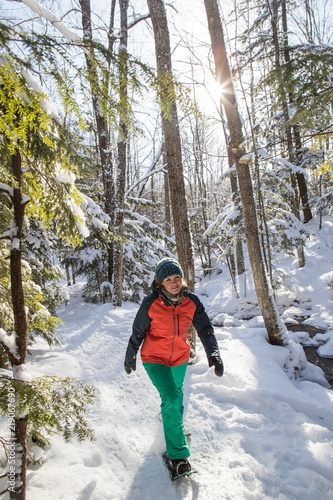 Beautiful woman snowshoeing in the forest.