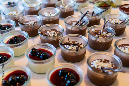 Closeup many dessert jar rowed up on buffet table with fresh fruits jelly and cream