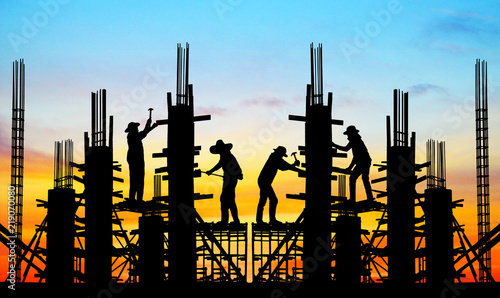 silhouette construction team working on high ground over blurred background sunset sky.