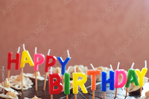 Happy birthday cake for party decorated with colorful candles on grunge pink background with copy space for text.