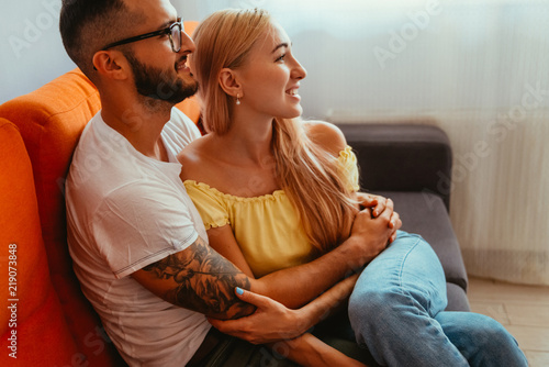 Attractive young couple cuddling on a couch at home