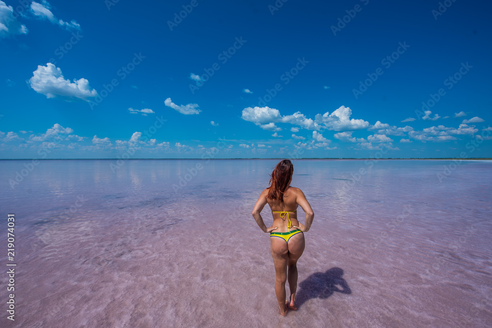 Girl standing on the ankle in a salt pink lake in the Altai. the girl in a candid  yellow bikini stands back with her bare buttocks. Miracle of nature rose lake