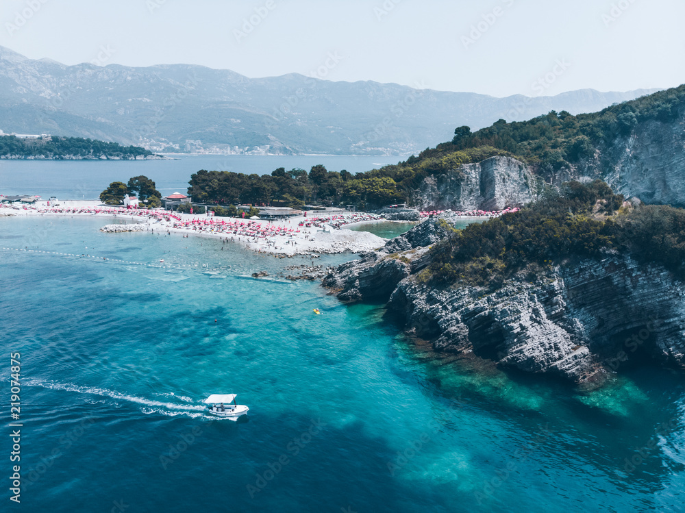 aerial view of sunny beach with rocky cliff