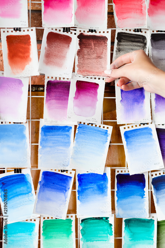 Obraz premium watercolors swatch assortment background. ink dyes colors mix on paper. art painting and drawing. inspiration and creativity. artist skills practice. free space concept. woman hand choosing.