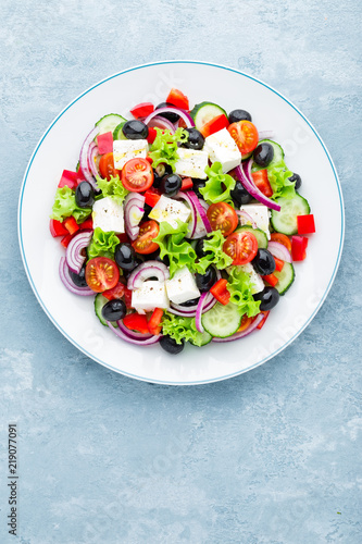 Greek salad of fresh cucumber, tomato, sweet pepper, lettuce, red onion, feta cheese and olives with olive oil