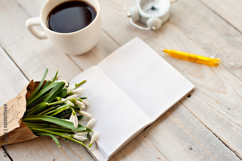 Cup of coffee, bouquet of flowers, notebook and the handle on a light wooden background Cup of coffee, bouquet of flowers, notebook and the handle on a light wooden background