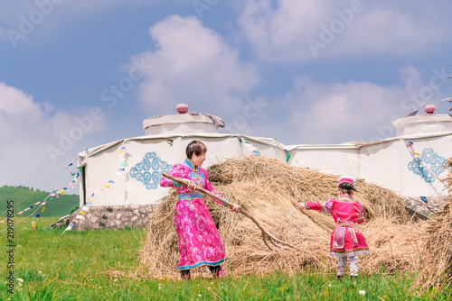 Mongolian mother and daughter working in front of the grass
