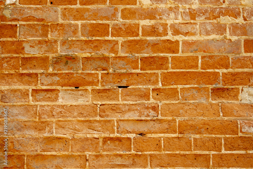 Fototapeta premium Chipped red brick in an ancient wall during the restoration. Restoration of plaster and whitewashed brick wall of the 1600s. Restoration of plaster of an ancient brick wall by masters-restorers.