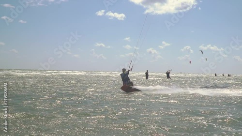 Kitesurfer perform tricks riding on the sea on a summer day, slow motion photo