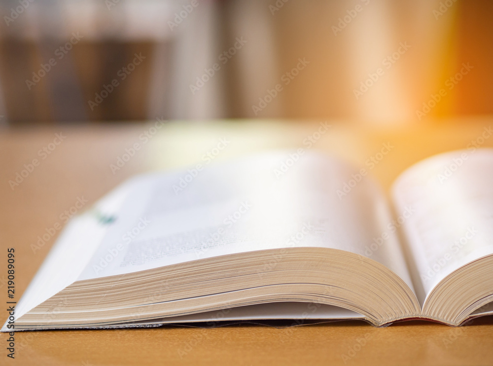 Close-up of open book on desk with sun light effect blur background. Close-up of open book on desk with sun light effect blur background.