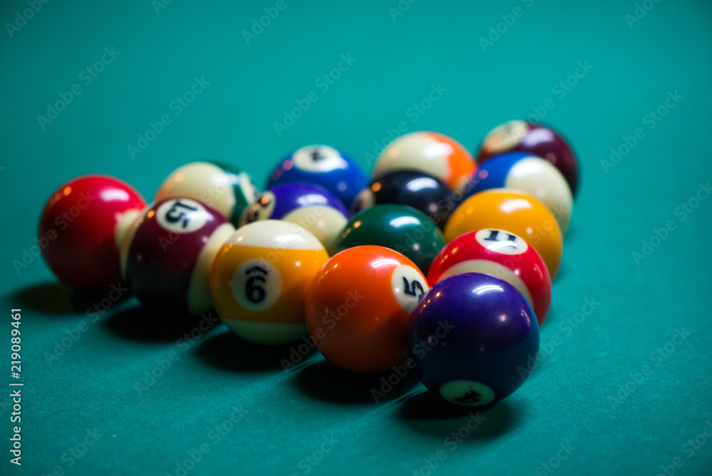 Sport billiard balls set arranged in shape of triangle on green billiard table in pub. Players are ready for the first hit of the round to start the billiard game Sport billiard balls set arranged in shape of triangle on green billiard table in pub. Players are ready for the first hit of the round to start the billiard game