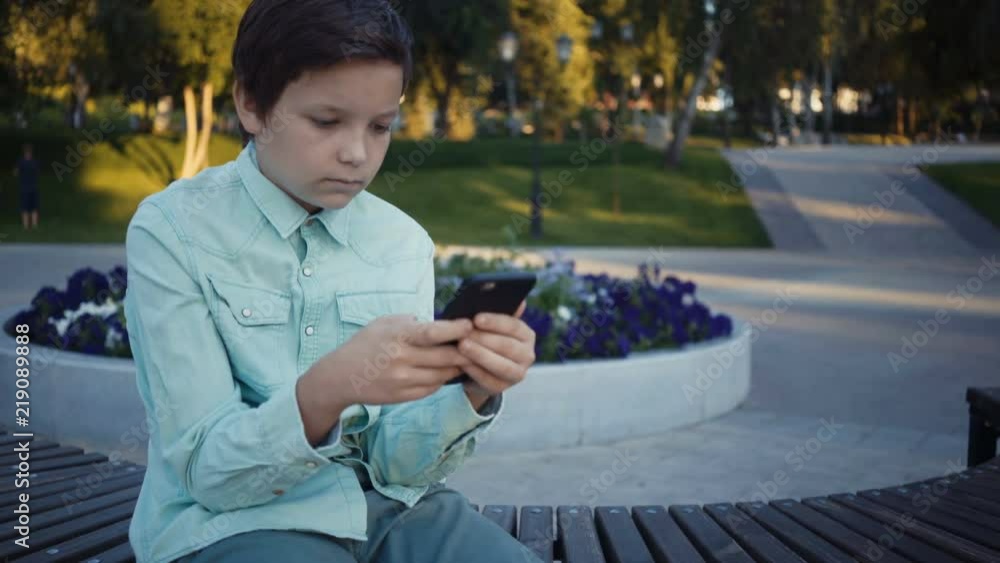 teenager playing video games on his smartphone outdoors. teenager playing video games on his smartphone outdoors.