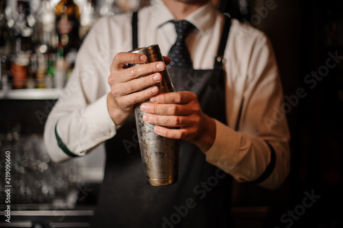 Professional male bartender holding a steel shaker photo
