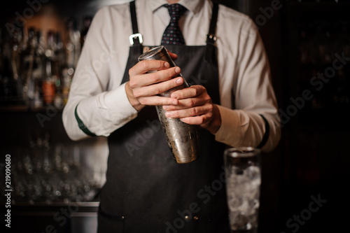 Professional bartender holding a steel cocktail shaker