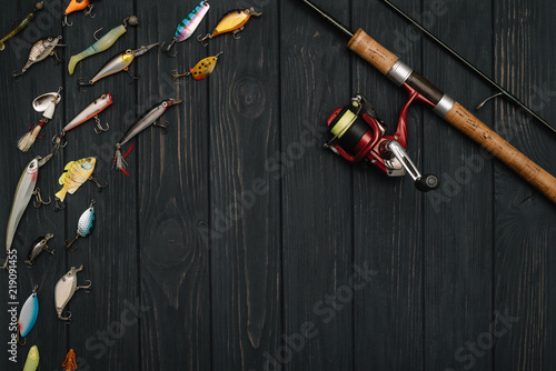 Fishing tackle - fishing spinning, hooks and lures on darken wooden background. Top view. photo