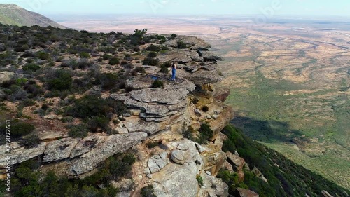 Woman standing on the edge of a high cliff enjoying a breathtaking view