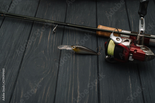 Fishing tackle - fishing spinning, hooks and lures on darken wooden background. Top view. photo