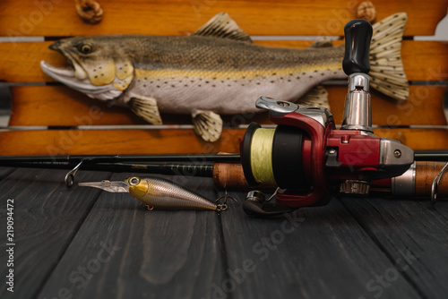 Fishing tackle - fishing spinning, hooks and lures on darken wooden background. Top view. photo