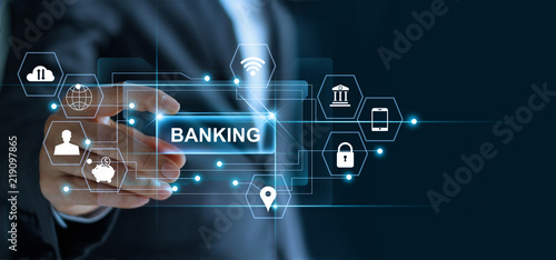 Businessman holding word banking in hand with icon network connection on virtual screen dark background