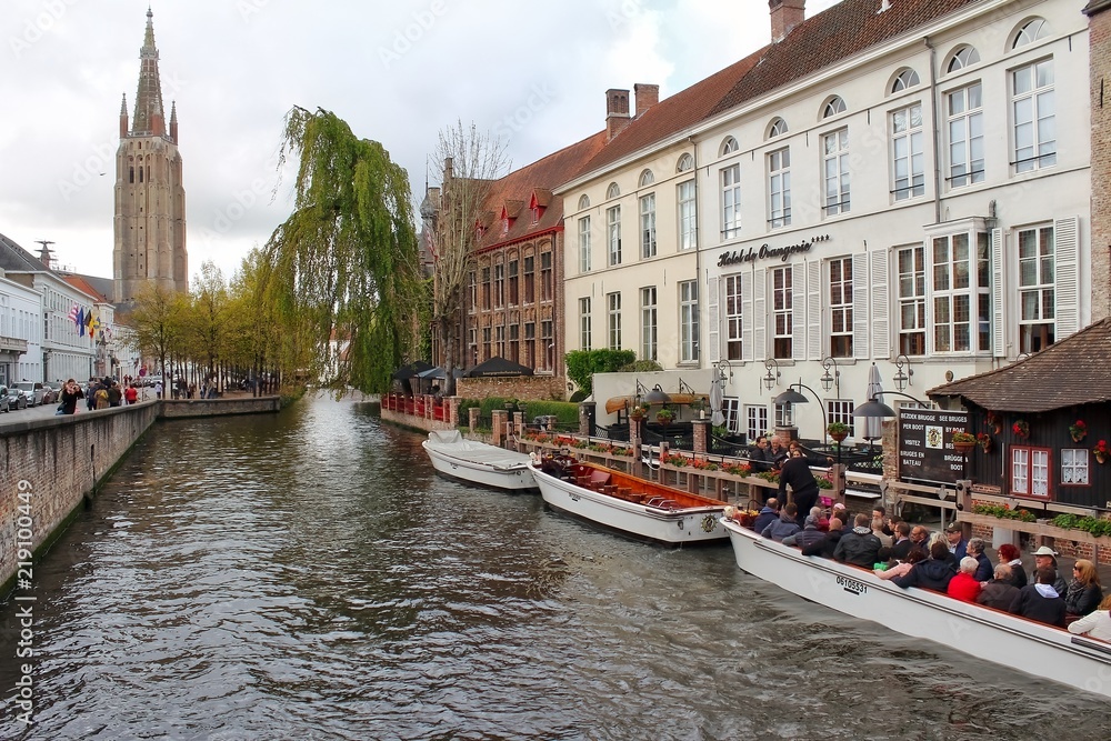 tourist boat going down canal in bruges belgium in autumn 