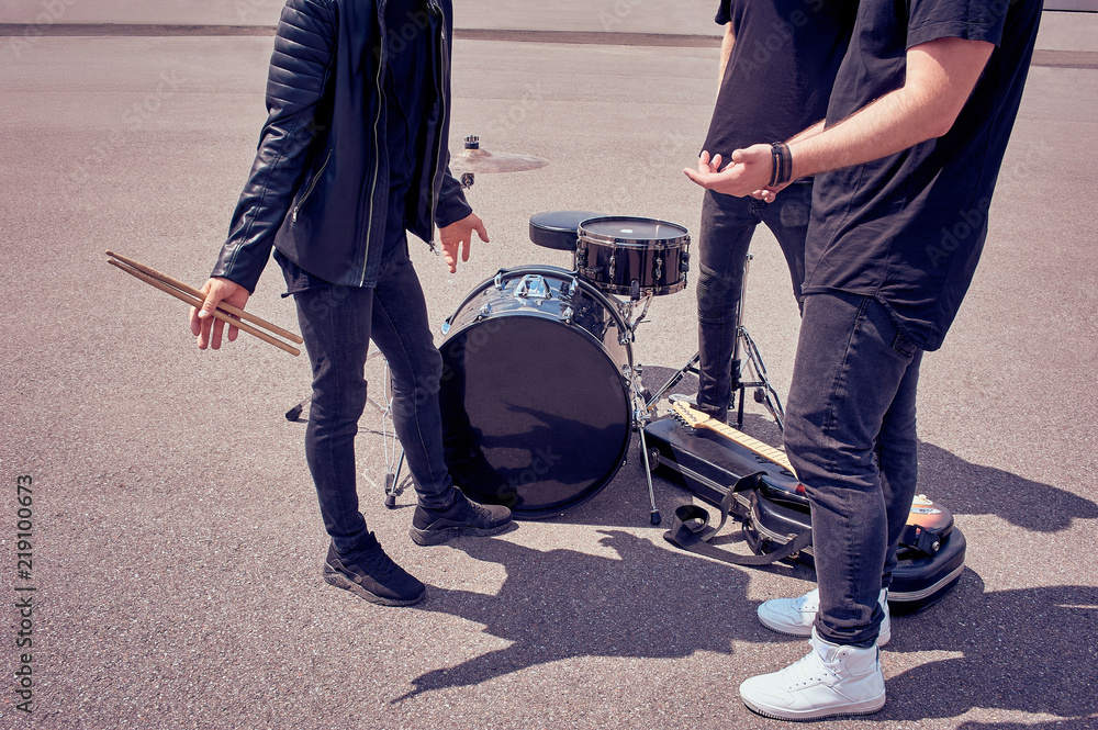 partial view of rock band in black clothing standing near musical instruments on street partial view of rock band in black clothing standing near musical instruments on street