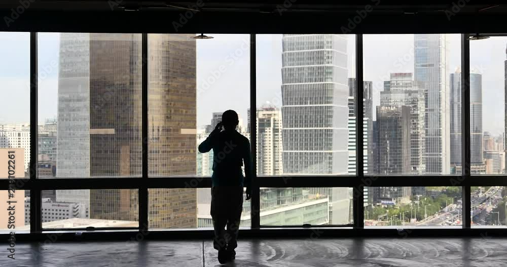 4k,businessman makes a phone call as overlooking the urban business building from window,skyscrapers,economic center. 4k,businessman makes a phone call as overlooking the urban business building from window,skyscrapers,economic center.