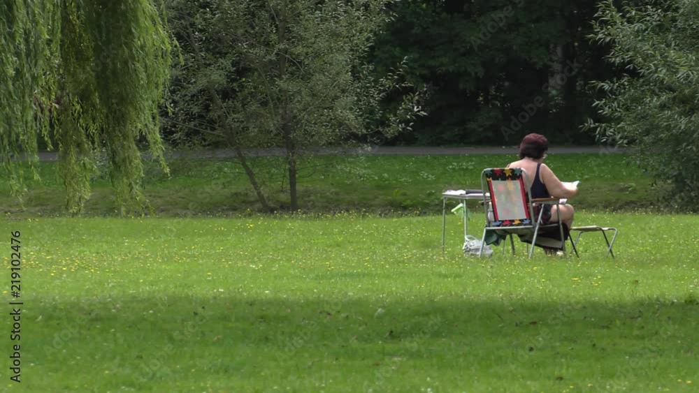 Couple relaxing on a deck chair. Woman lying and reading a book.Panning, Couple relaxing on a deck chair. Woman lying and reading a book.Panning,