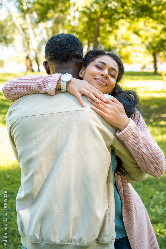 african american boyfriend and girlfriend cuddling in park