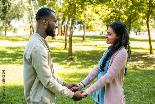 smiling african american couple holding hands and looking at each other in park © LIGHTFIELD STUDIOS