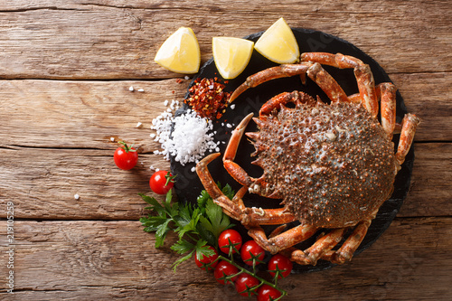 Seafood background: raw edible spider crab with ingredients close-up on a wooden table. Horizontal top view photo