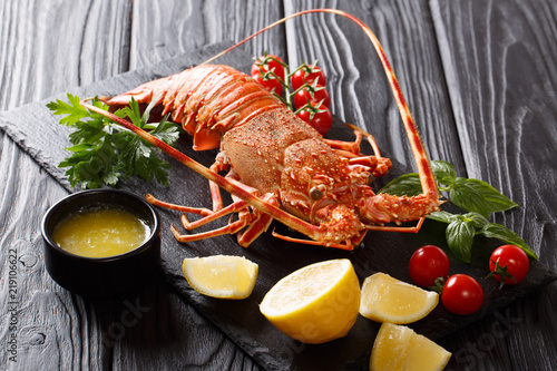 Φωτογραφία Prepared sea crayfish or spiny lobster with vegetables and melted butter close-up on a black
