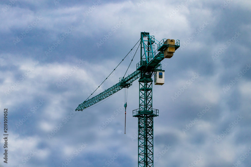 Construction cranes on the construction site against the blue sky and clouds Construction cranes on the construction site against the blue sky and clouds