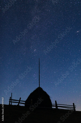 Silhouette of a straw stack against the night sky with stars and visible Milky Way