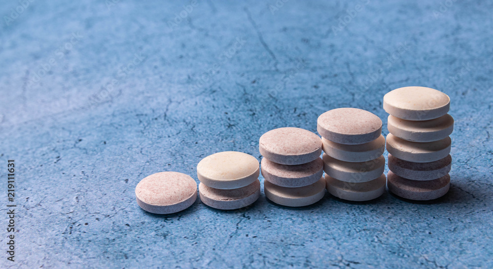 round vitamins stacked pyramid on a blue background round vitamins stacked pyramid on a blue background