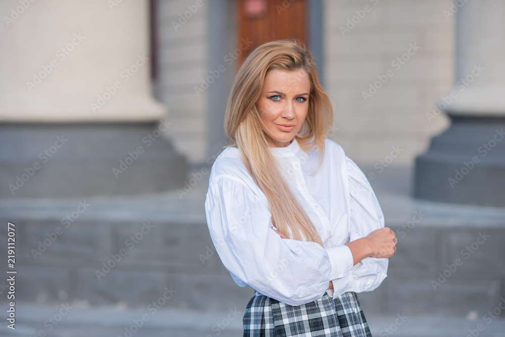 portrait of a blonde on a building background with columns. beautiful blonde in a white blouse smiling portrait of a blonde on a building background with columns. beautiful blonde in a white blouse smiling