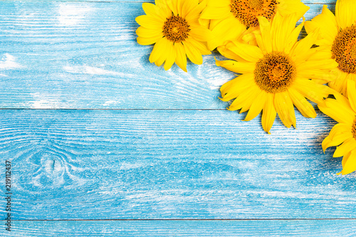 Yellow sunflowers on blue wooden background. Copy space.