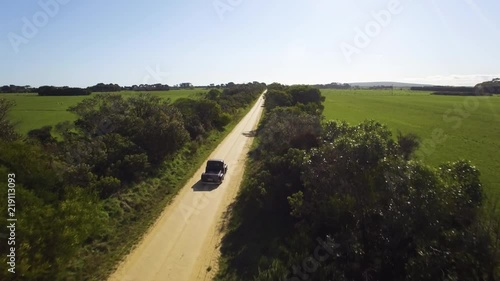 Drone following old car driving down lonely dirt road in country Victoria.