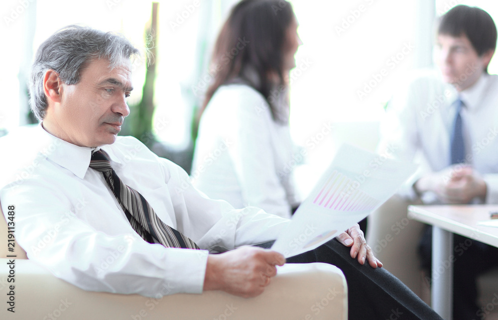 businessman pondering a document sitting in a modern office businessman pondering a document sitting in a modern office