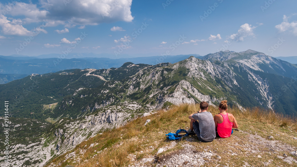 Fototapeta premium Couple sitting on the top of the Vogel mountain in the Triglav Park.