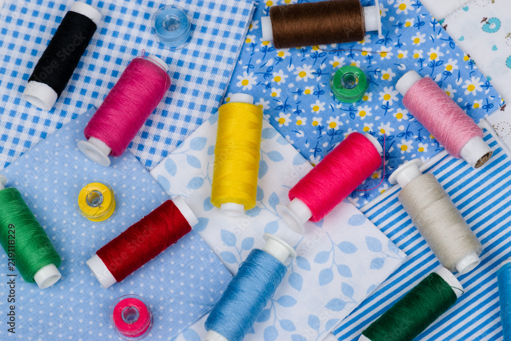 Multicolored threads, buttons on blue fabric Multicolored threads, buttons on blue fabric