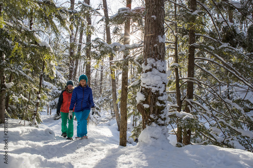 Obraz na płótnie Pair of female friends snowshoeing in forest. w salonie