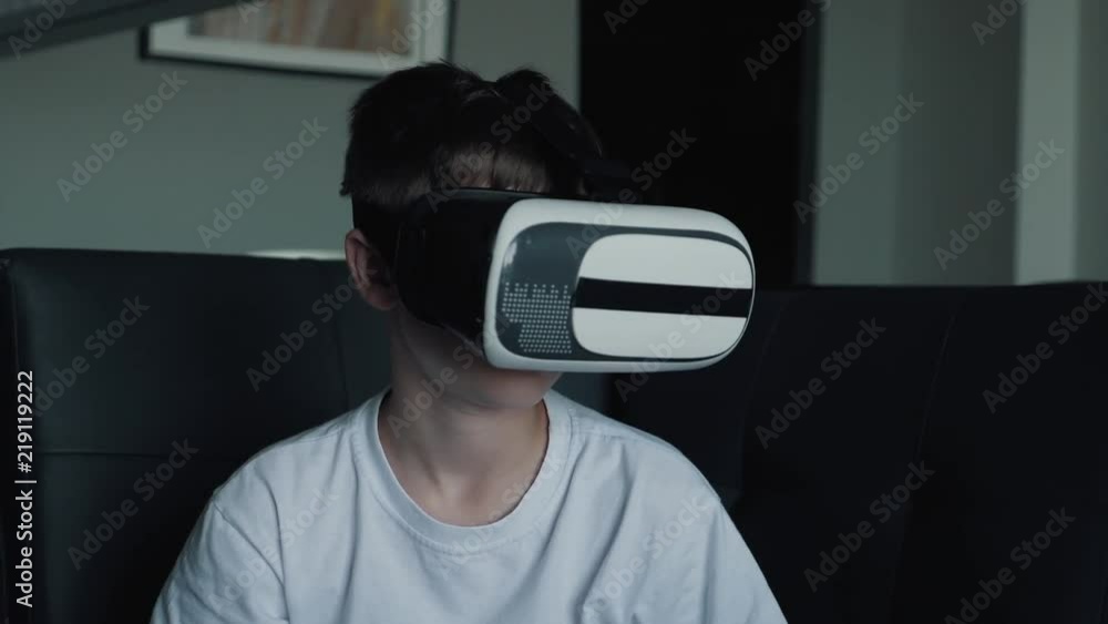 A happy boy with virtual reality glasses at home playing games and watching movies. VR glasses new technologies A happy boy with virtual reality glasses at home playing games and watching movies. VR glasses new technologies