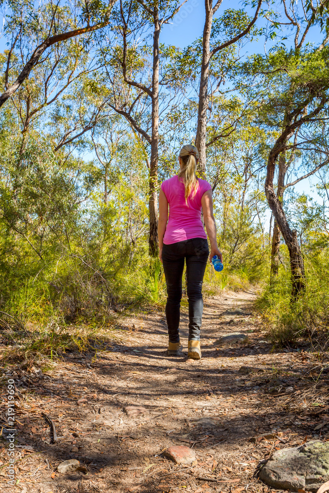 Female walking along a bush track among nature Female walking along a bush track among nature