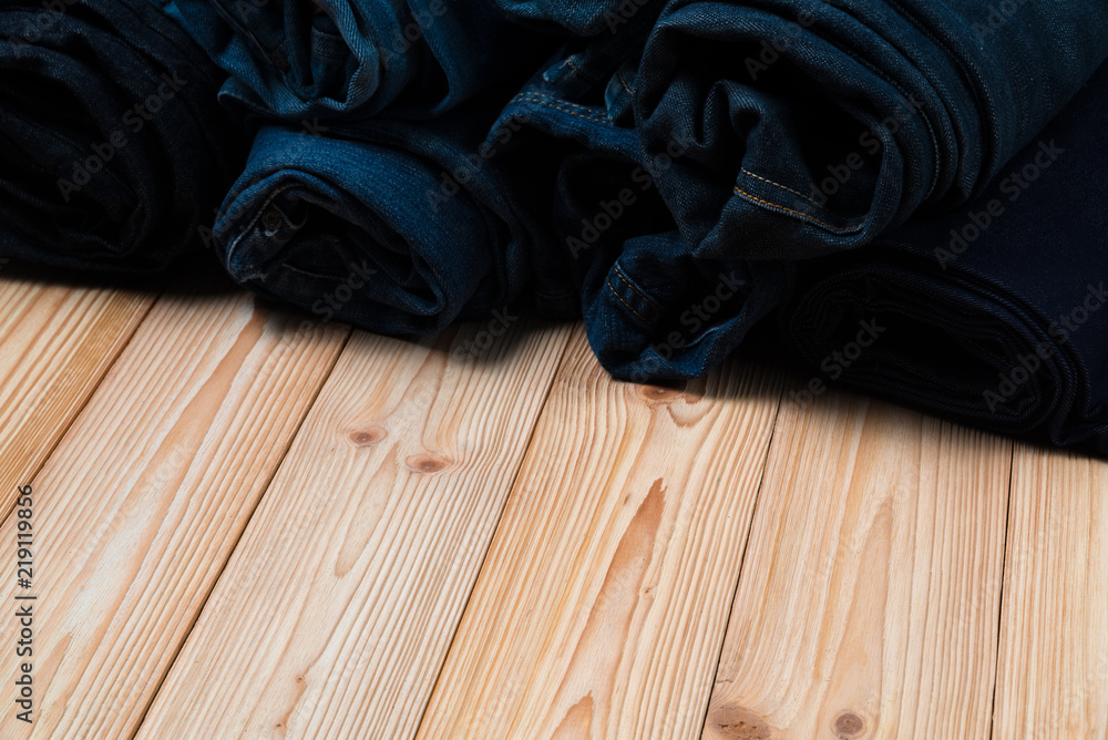 Roll Frayed jeans or blue jeans denim collection on rough wooden table background with copy space, old fashion concept. Roll Frayed jeans or blue jeans denim collection on rough wooden table background with copy space, old fashion concept.
