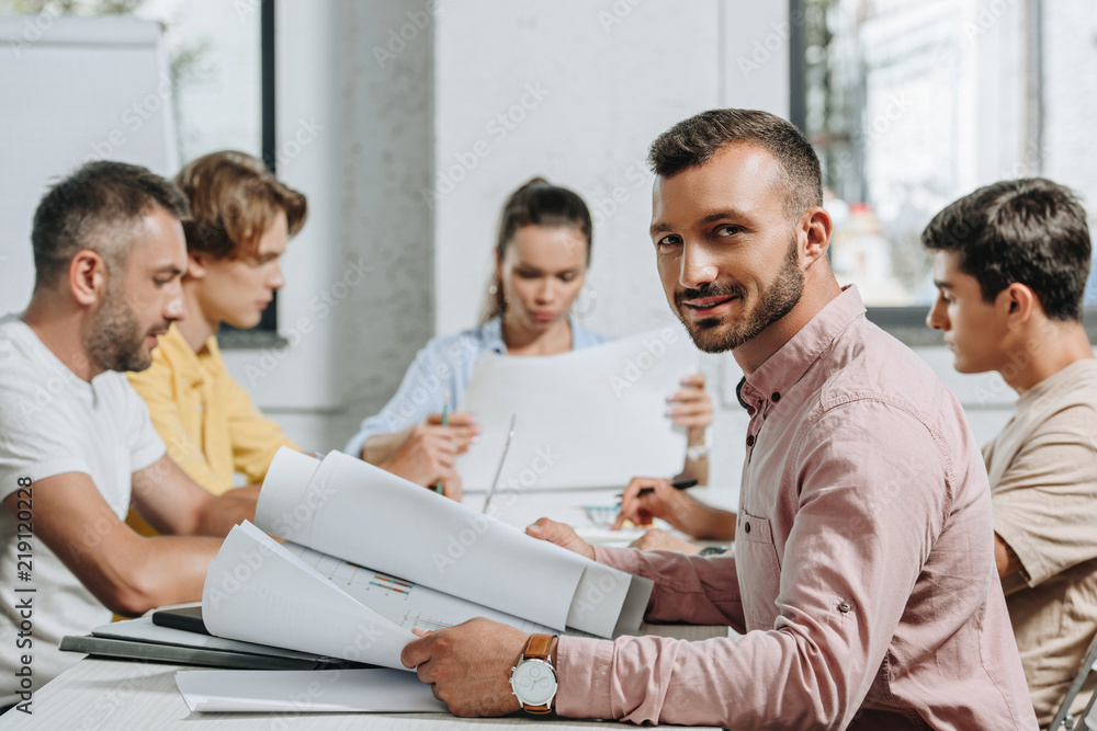 Fototapeta premium handsome businessman looking at camera during meeting in office