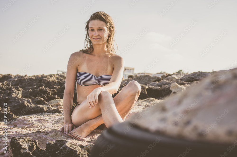 Young woman with wet hair sunbathing on stones