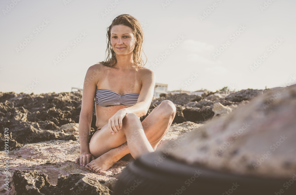 Young woman with wet hair sunbathing on stones Young woman with wet hair sunbathing on stones