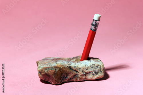 Pencil in stone like king Arthur sword. Writer hard job concept. Minimalism. Pastel colours background. Text and copy space. Trendy colors.