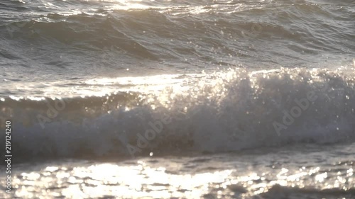 Big waves on a sea beach at sunset. Beautiful waves of slow motion video on the background of the orange sun photo