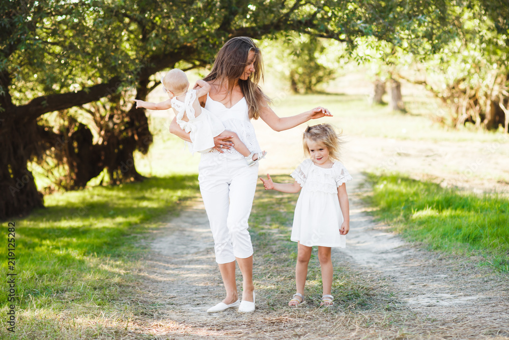 Mom with two little daughters are walking among the beautiful green forest. Mom with two little daughters are walking among the beautiful green forest.
